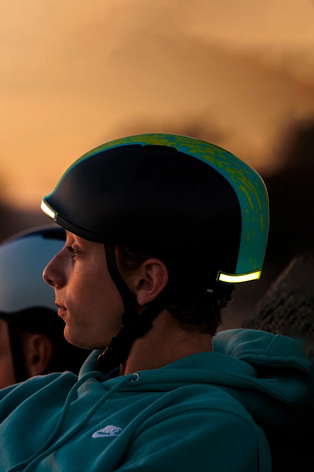 Teen at sunset wearing Lumos Nyxel Kids in Green Overspray with the lights on